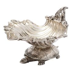 an ornate silver bowl on top of a turtle