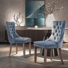 two blue chairs sitting next to each other in front of a vase on a table