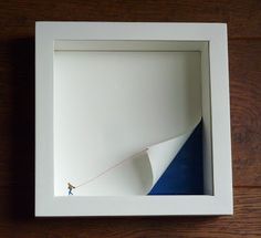 a person is flying a kite in a white box on the floor with wood floors