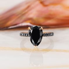 a black diamond ring sitting on top of a white table next to an orange shell