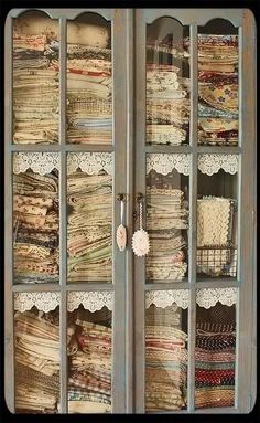 an old china cabinet filled with lots of fabric