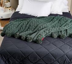 a green blanket on top of a bed next to pillows