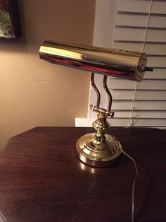 a desk lamp sitting on top of a wooden table next to a window with shutters