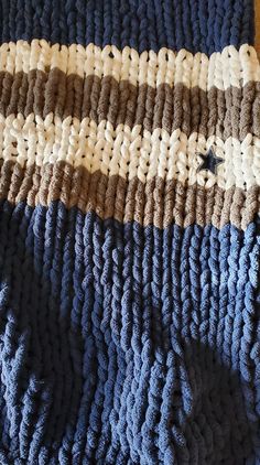 a blue and white knitted blanket laying on top of a wooden floor next to a wall