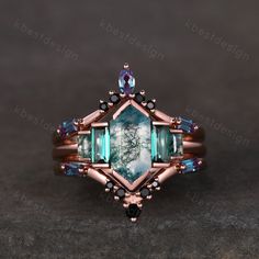 a ring with green and blue stones on it's sides, sitting on top of a table