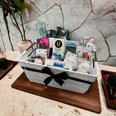 a white basket filled with personal care items on top of a wooden cutting board next to a potted plant