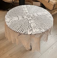 a white table topped with a doily covered round tablecloth on top of a hard wood floor