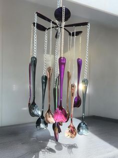 a chandelier hanging from the ceiling with several different colored spoons attached to it