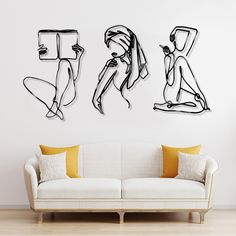 three black and white drawings on the wall above a couch in a room with wood flooring