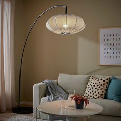 a living room with a couch, coffee table and floor lamp in the middle of it