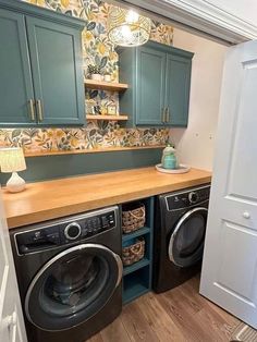 a washer and dryer in a small room with green cupboards on the wall