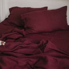 an unmade bed with red sheets and pillows