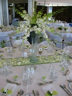 there is a vase with white flowers on the table set for a formal dinner or party