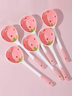 six spoons with strawberry designs on them are lined up against a pink background,