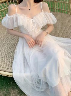 a woman in a white dress sitting on a wicker chair