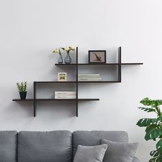 three shelves on the wall above a couch with books and vases sitting on it