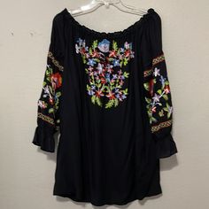 This Elegant And Exquisite Off Shoulder Top By Chelsea & Theodore Has Vibrant Floral Embroidery; A Rounded Neckline That Ties In The Front; And ¾ Length Sleeves With An Elasticized Ruffle At The Bottom. It Is An Absolutely Beautiful Top For Career Or Any Dress Up Occasion. Size Medium Nwt Pit To Pit About 20”Length About 28” Very Stretchy Has 2 Pockets On Side Rayon Black Long Sleeve Embroidered Top With Floral Print, Black Summer Blouse With Embroidered Sleeves, Black Embroidered Hem Blouse For Spring, Black Blouse With Embroidered Hem For Spring, Black Embroidered Hem Top For Summer, Black Embroidered Top With Spring Sleeves, Spring Black Top With Embroidered Sleeves, Black Long Sleeve Embroidered Top, Black Long Sleeve Embroidered Top For Summer