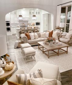 a living room filled with white furniture and lots of pillows on top of it's couches