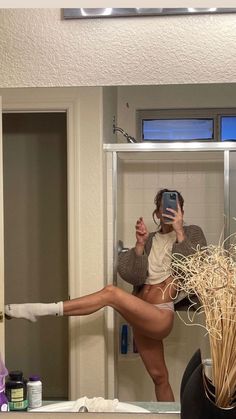 a woman taking a selfie in front of a mirror with her legs spread out