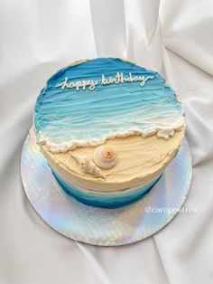 a birthday cake that is decorated with the ocean and beach scene on it's side