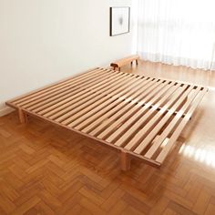 a wooden bed frame sitting on top of a hard wood floor next to a window