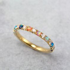 a yellow gold ring with opal and white diamonds on the side, sitting on a gray surface