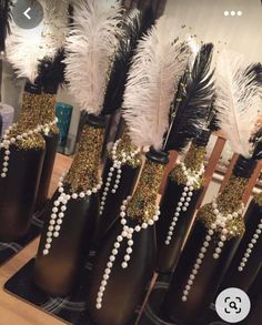 some black vases with white and gold decorations in them on a table next to a mirror