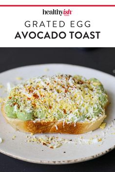 an avocado toast on a white plate with sprinkled parmesan cheese