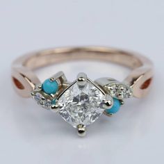 a diamond and turquoise stone ring on a white surface