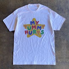 My tummy hurts tee is the perfect funny shirt to wear as your next meme shirt. Inspired by clowncore clothing and kidcore clothes - the playful colors and original hand written lettering will surely bring colors to your days. This funny meme shirt is a perfect addition to your kidcore tee collection or as your daily clown shirt. This clowncore shirt is also the perfect funny gift for her, gift for him or anyone you know who suffers from IBS, survived a diarrhea or for anyone you love who always Silly T Shirt Design, Silly Clothes Aesthetic, Weird Shirts Aesthetic, Silly Shirt Ideas, Character Shirt Design, My Tummy Hurts Shirt, Cursed Tshirt Designs, Shirts That Go Hard, Silly T Shirts