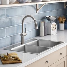 a stainless steel kitchen sink and faucet in front of blue tiled backsplash