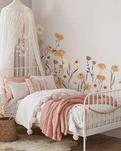 a white bed with pink and yellow flowers on the wall