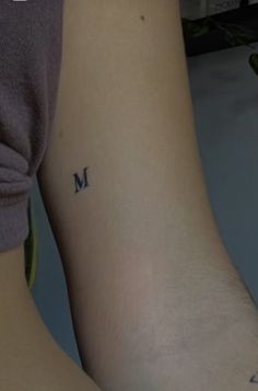 two people with matching tattoos on their arms, one has the letter m and the other has an arrow