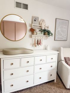 a white dresser with drawers and a mirror on the wall next to a couch in a living room