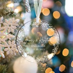 a personalized ornament hanging from a christmas tree with lights in the background