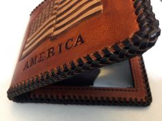 "A Patriotic USA Pride hand-made Leather Bi-fold wallet Features a hand-tooled American Flag design. An outstanding way to proudly display your love for our great country. *Only one of these exists and this one is being offered at a special discount price.* This wallet is 100% Made-In-America DETAILS: - Double looped genuine calf lace - 3 tone dye finish- ( Tan, Dark Brown, Natural) Eco-friendly waterproof finish - Crafted from Herman Oak veg tanned leather- the best hands down - Interior premiu Custom Handmade Trifold Wallet, Custom Handmade Rectangular Trifold Wallet, Customizable Leather Bifold Wallet, Customizable Brown Bifold Wallet, Custom Rectangular Trifold Wallet With Coin Pocket, Custom Rectangular Wallets As Gifts, Custom Rectangular Wallets For Gift, Usa Pride, American Flag Design