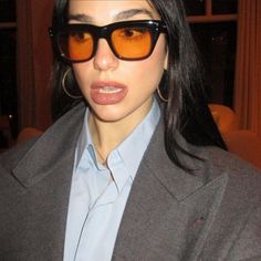 a woman wearing sunglasses and a blue shirt is looking at the camera with an intense look on her face