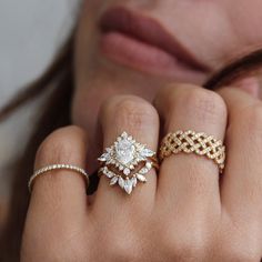 a woman's hand with three different rings on her fingers and one ring in the middle