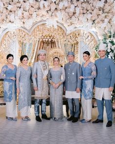 a group of people standing next to each other in front of a flower covered wall