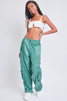 It’s giving off-duty vibes! Our Women's High-Rise Rouched Nylon Jogger is the perfect baggy pant to add to your wardrobe! Designed with an adjustable bungee cord at the elasticized waistband for the perfect fit and comfort. These high waisted pants are meant to be oversized with a baggy and slouchy fit. Featuring silver hardware and large cargo pockets for a sporty-chic vibe. We’ve also added adjustable bungee cords at the bottom hems to give you the option of wearing them more scrunched up at the ankle. Pair these with a crop top and sneakers for a sporty look, or pair with a corset top and combat boots for an edgier feel. Product Details - High-Rise - Elasticized Waistband with Bungee- Single Zip Close Pocket at Thigh- 2 Flap Cargo Pockets at Lower Side - Baggy Fit - Drawstring Hems Size Sporty Parachute Pants For Summer Outdoor, Sporty Summer Parachute Pants For Outdoor, Trendy Green Parachute Pants With Elastic Waistband, Summer Nylon Pants With Functional Drawstring, Summer Nylon Drawstring Pants, Summer Utility Parachute Pants For Outdoor Activities, Trendy Green Nylon Bottoms, Urban Parachute Pants With Elastic Waistband For Summer, Summer Nylon Streetwear Pants