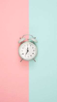 an alarm clock sitting on top of a pink and blue wall next to each other