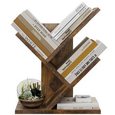 a stack of books sitting on top of a wooden stand next to a bowl filled with plants