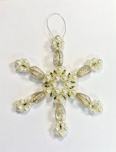 a white snowflake ornament with pearls hanging from it's side