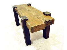 a wooden bench made out of wood with metal legs and feet on the top, sitting on a tile floor