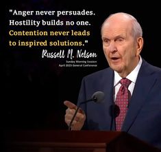 a man in a suit and tie speaking at a podium with a quote on it