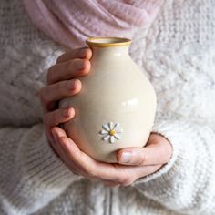 a woman holding a small vase in her hands