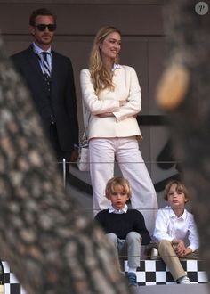 two men and one woman are standing on the sidelines with their arms crossed as they look at each other