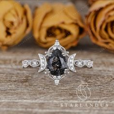 a black and white diamond ring on top of a wooden table with roses in the background