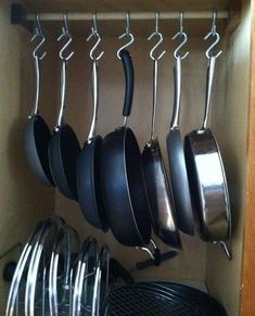 pots and pans hanging from hooks in a cabinet