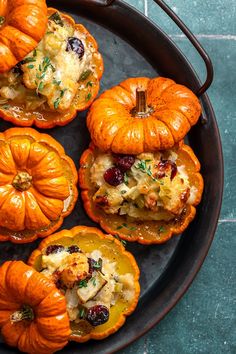 four mini pumpkins with stuffing and cranberries in them on a black plate